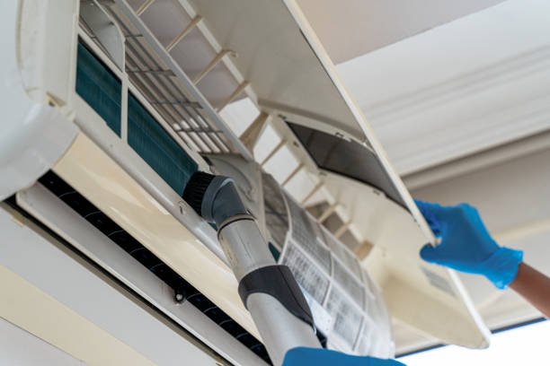 Back female worker holds a brush from a portable steam generator for maintenance of an air conditioning system, emphasizing AC system maintenance in Weston FL.